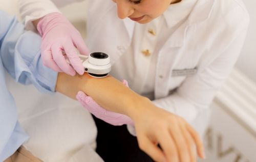 Provider checking a patients arm during a skin exam